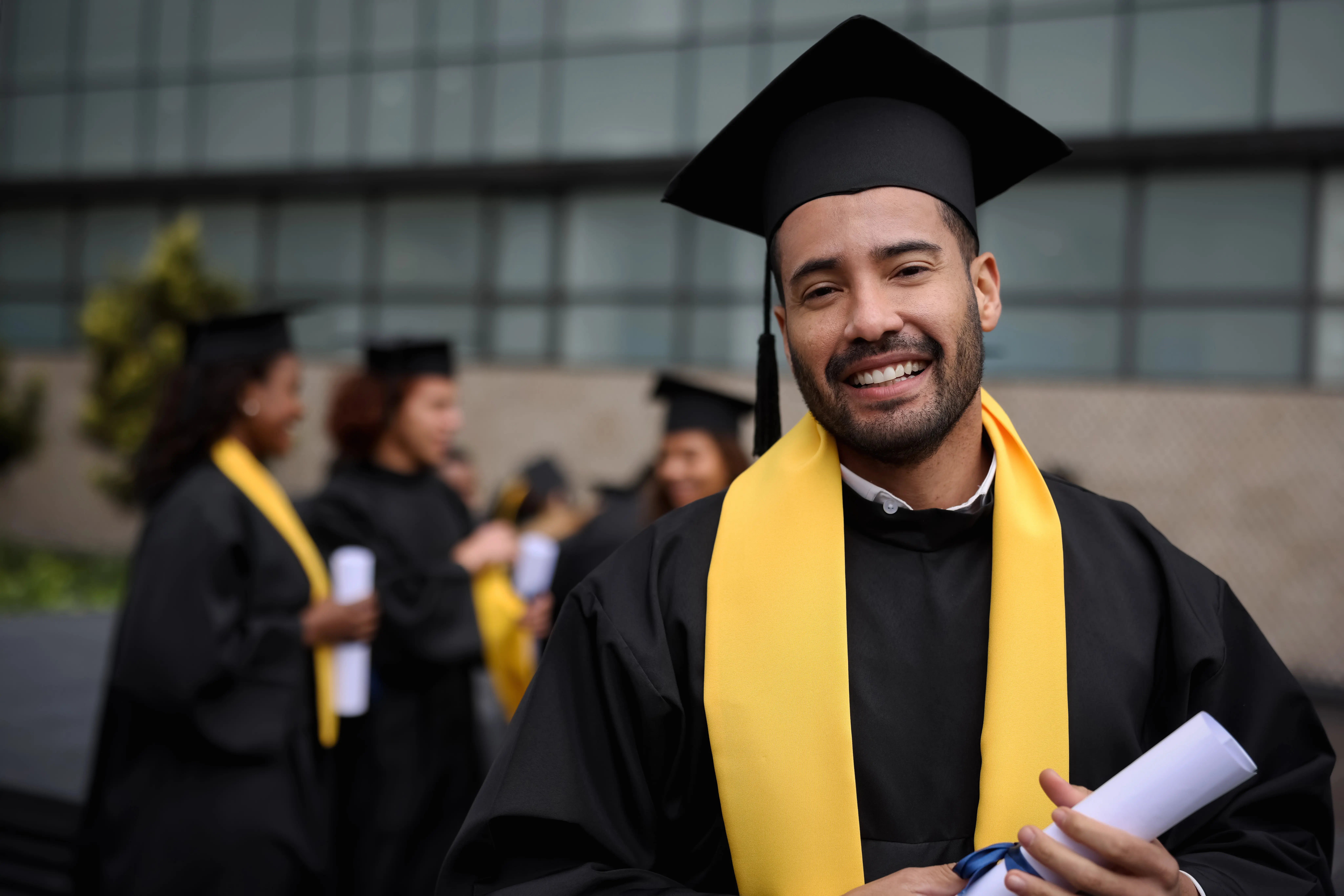 happy graduate student holding his diploma on graduation day