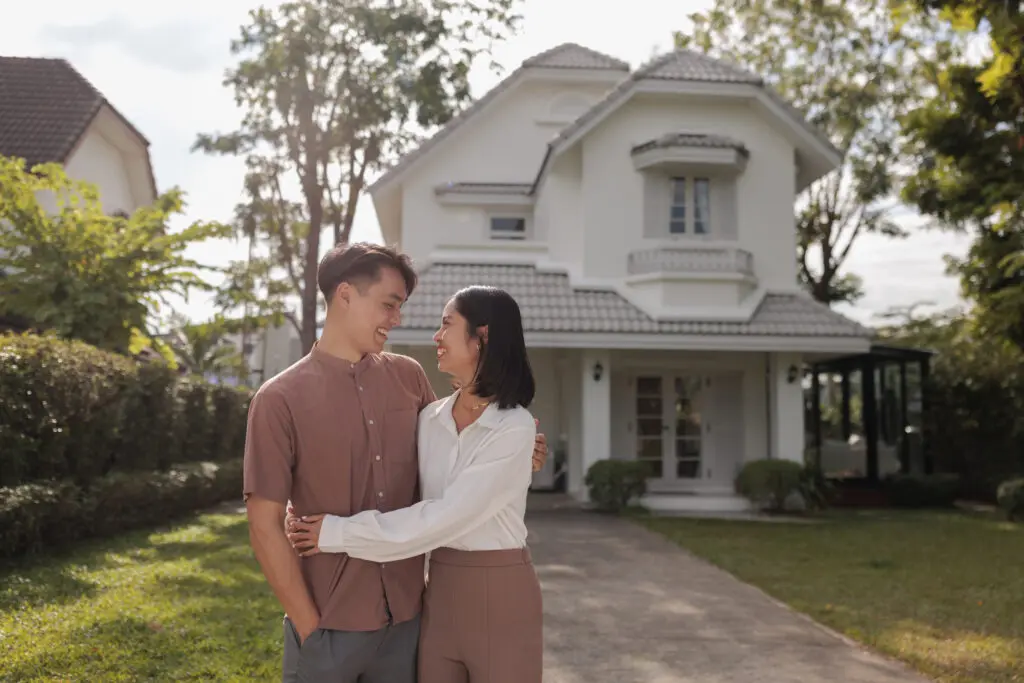 smiling couple in front of their new house