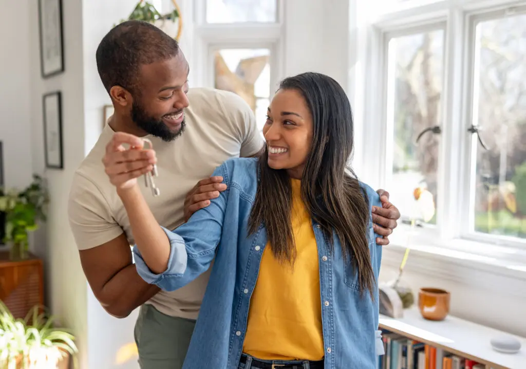 couple looking very happy holding the keys of their new house