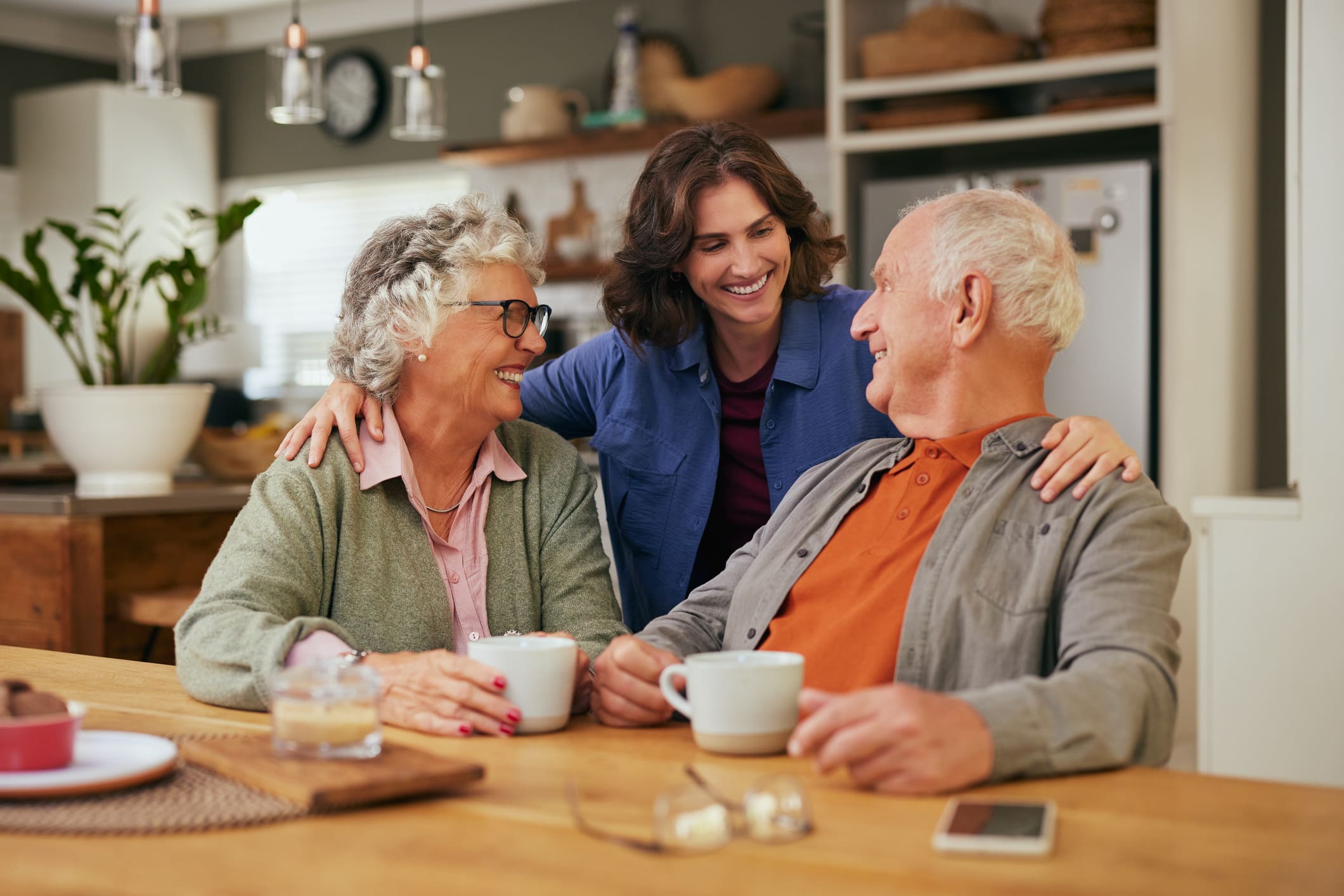 happy smiling senior parents with adult daughter drinking tea