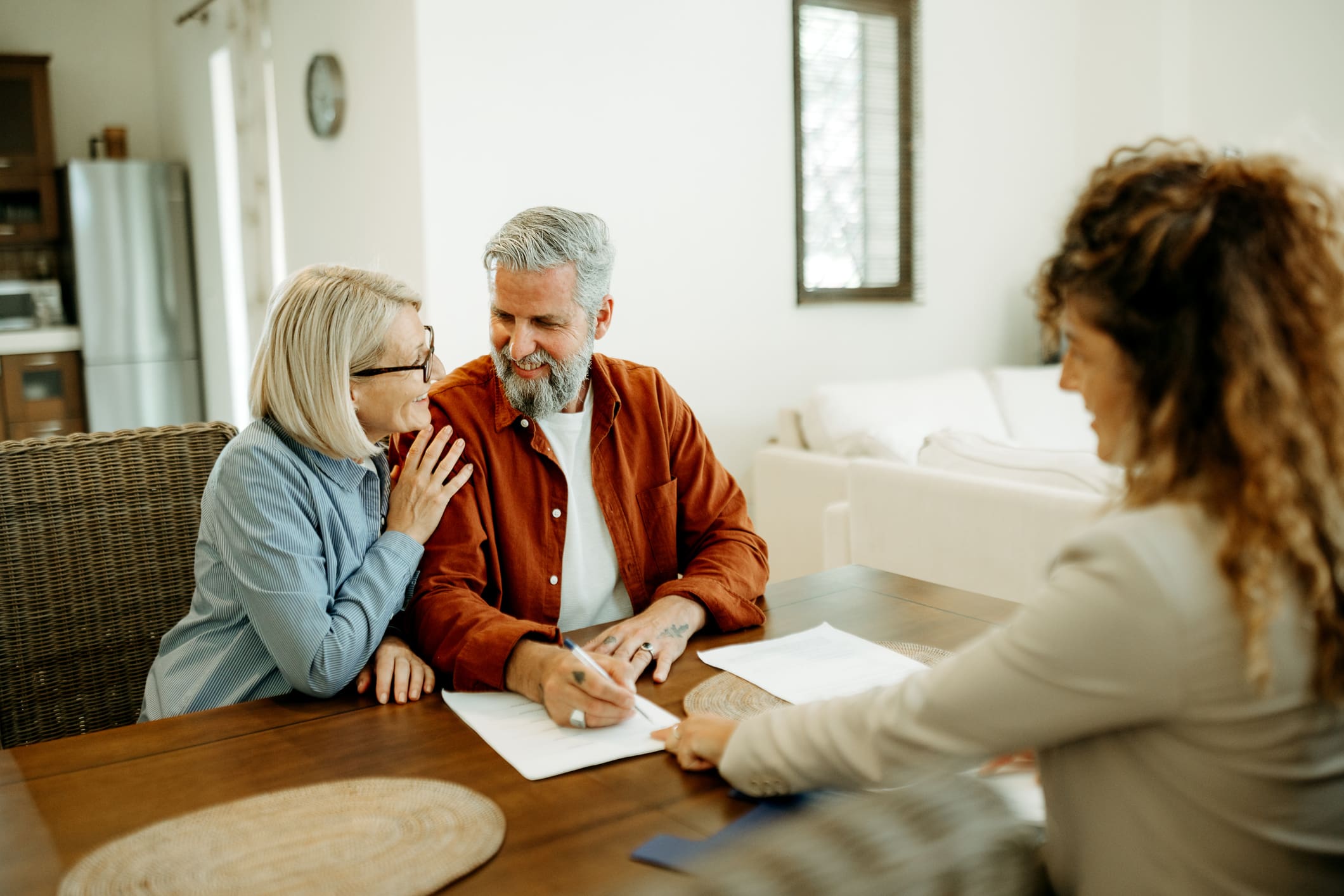 real estate agent going over paperwork with mature couple at their home